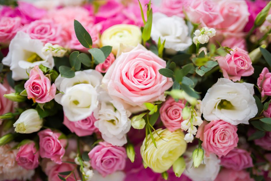 A vibrant floral arrangement featuring a mix of pink and white roses, complemented by white lisianthus and delicate white Paradise flowers, all arranged with fresh green eucalyptus leaves. The flowers